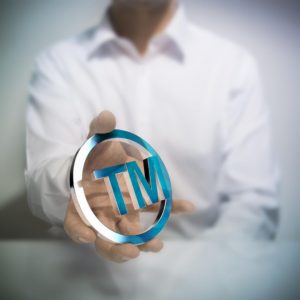 Man with trademark symbol in hand: MaxFilings Patents and Trademarks Blog